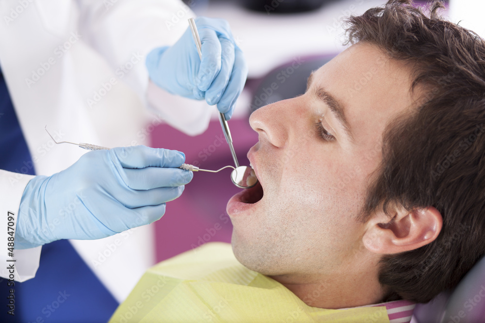 Young man getting his teeth cleaned by a dentist Young man getting his teeth cleaned by a dentist