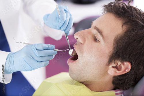 Young man getting his teeth cleaned by a dentist