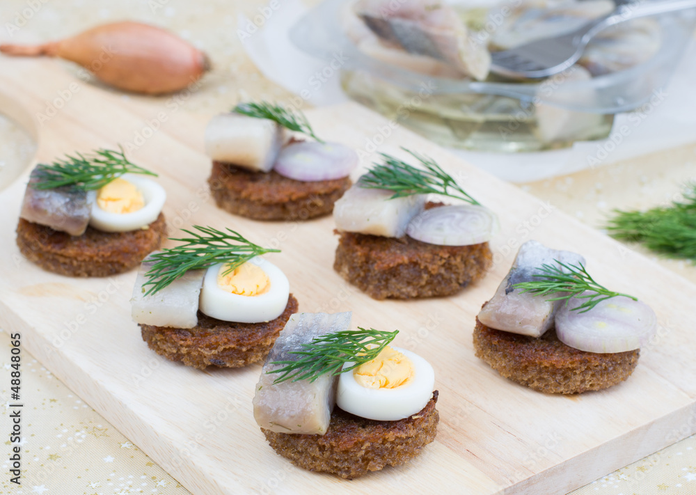 Small canapes with herring, eggs and shallot