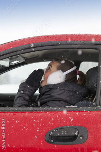 Cute girl with flu symptoms sneezes in a car on winter day