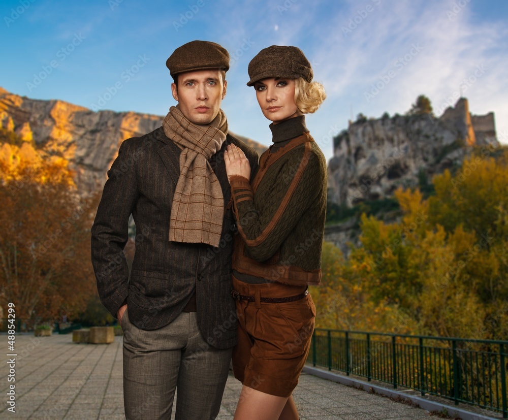 Elegant couple in caps against autumnal landscape
