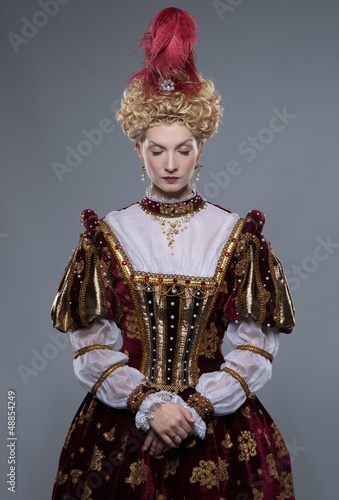 Haughty queen in royal dress isolated on grey
