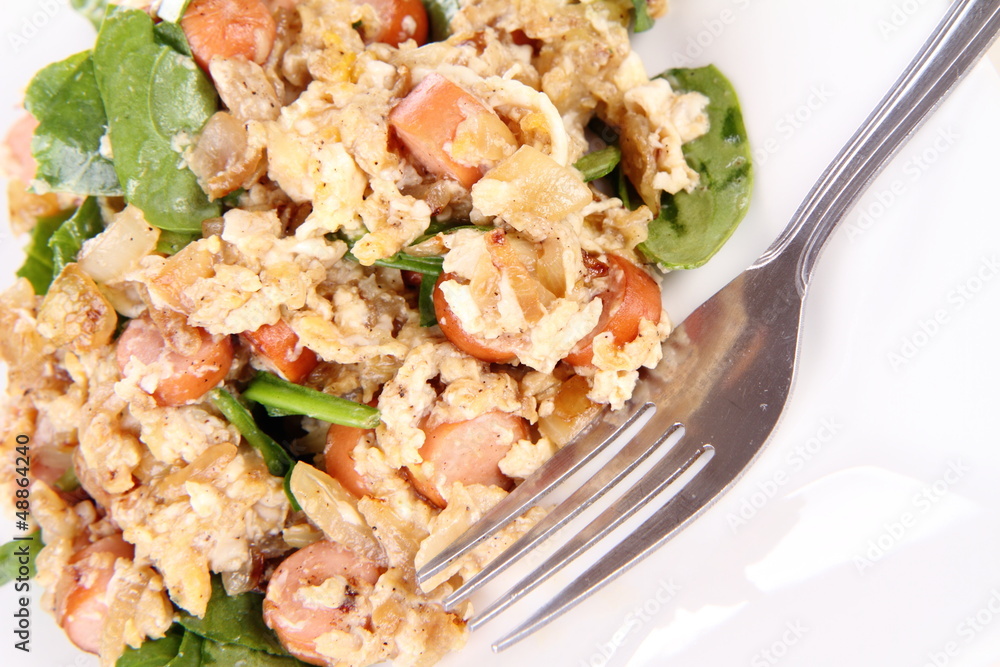 Scrambled eggs with frankfurters and spinach, and a fork Scrambled eggs with frankfurters and spinach, and a fork