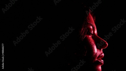 volto di ragazza che dorme e sogna nell'oscurità con luce rossa photo