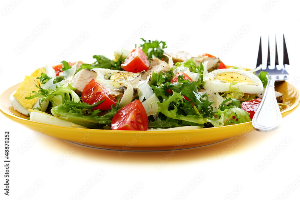 Salad with tomatoes, cheese and chicken in a yellow plate.