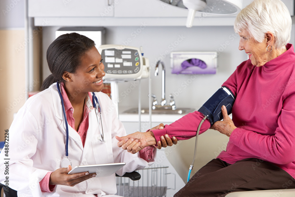 Fototapeta premium Doctor Taking Senior Female Patient's Blood Pressure