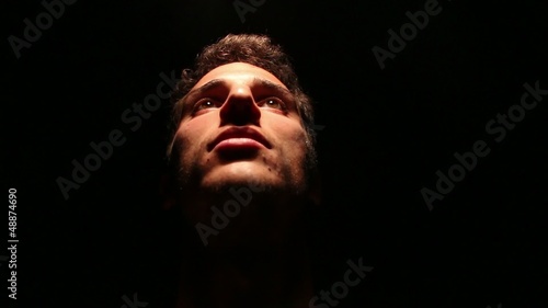 luce riflessa su volto maschile e sfondo nero photo
