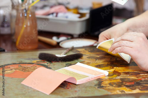 Restorer gilding on the old icon