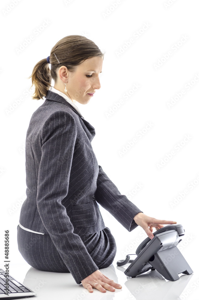 Businesswoman sitting on a white office desk with telephone Businesswoman sitting on a white office desk with telephone