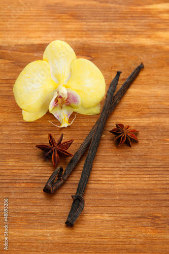 Fototapeta Naklejka Na Ścianę i Meble -  Vanilla pods and anise with flower, on brown wooden background