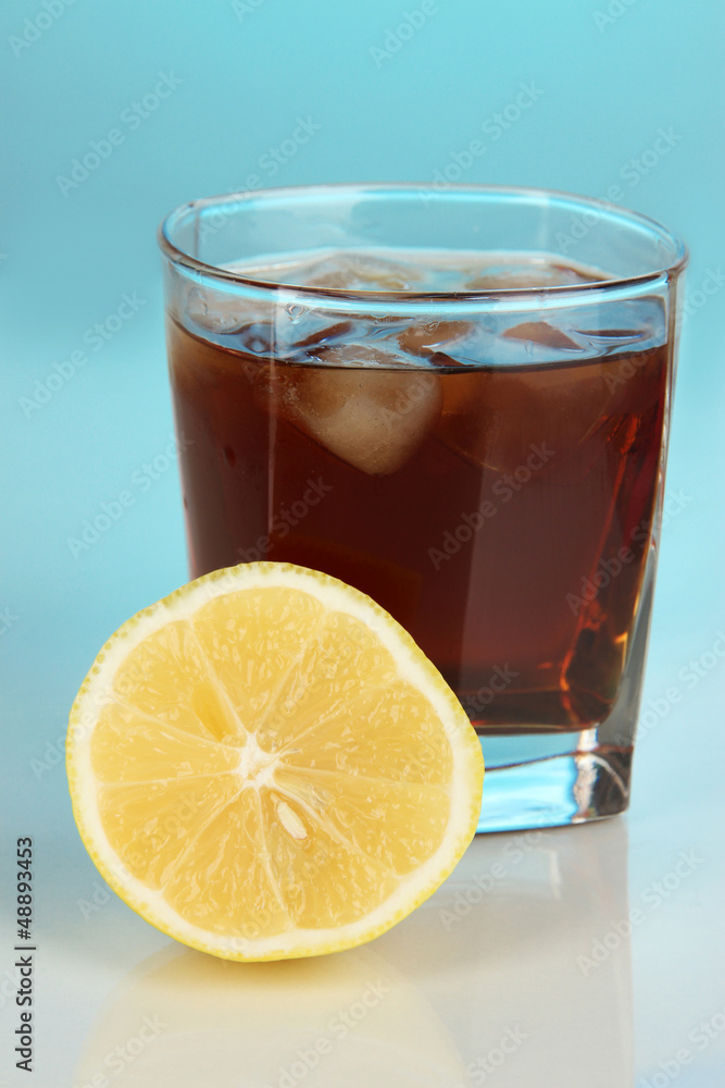 Glass of whiskey with ice and lemon on blue background Glass of whiskey with ice and lemon on blue background
