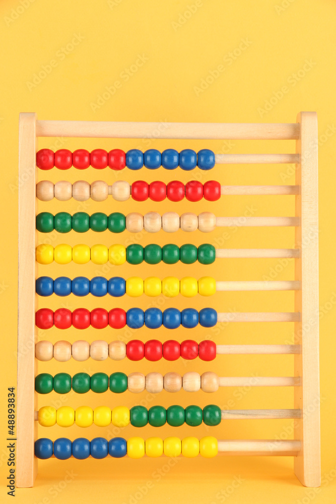 Bright wooden toy abacus, on yellow background Bright wooden toy abacus, on yellow background