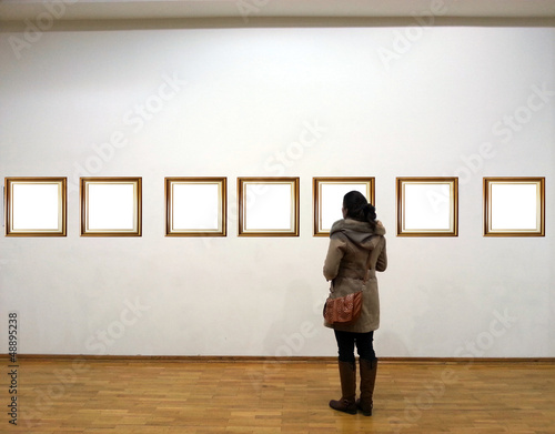 Woman in gallery room looking at empty frames