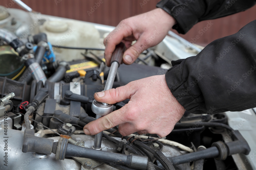 Mechanic servicing engine, ratchet and spark plug Mechanic servicing engine, ratchet and spark plug