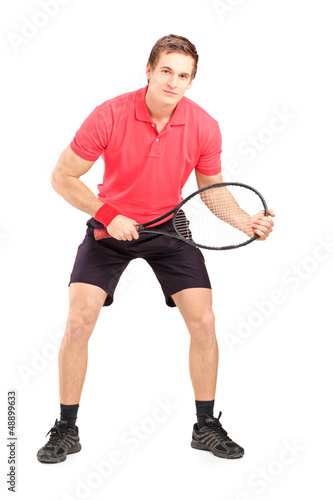 Full length portrait of a male tennis player holding a racket