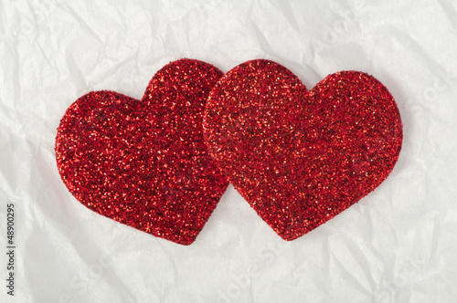 Shiny red hearts on white paper