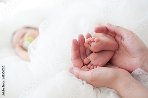 Women's hands holding baby feet