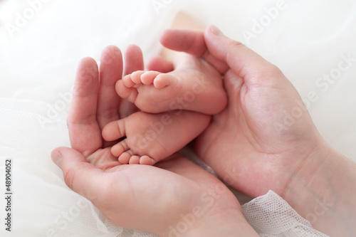 Women's hands holding baby feet.