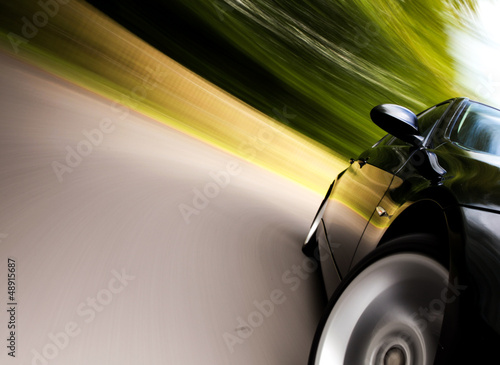 Side view of black car in turn with heavy blurred motion. © Aleksei Demitsev