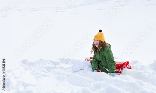 Girl with sleigh sitting in snow