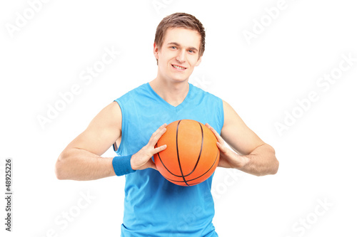A young basketball player holding a basketball and looking at ca