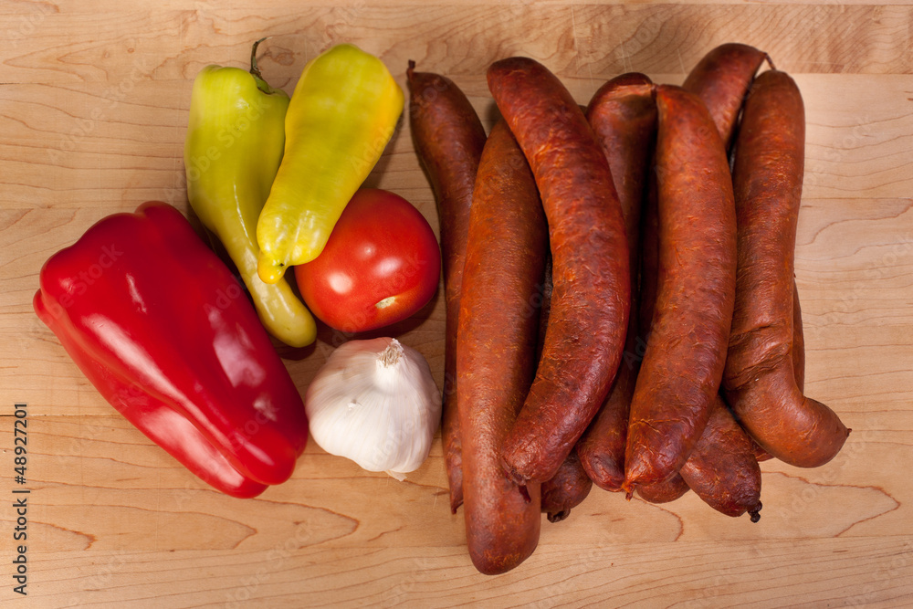 Sausages with pepper garlic and tomato on wooden background Sausages with pepper garlic and tomato on wooden background