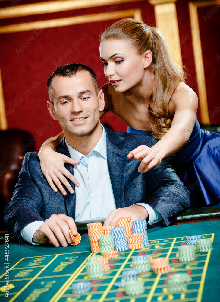 Man accompanied by woman placing bets at the casino Man accompanied by woman placing bets at the casino