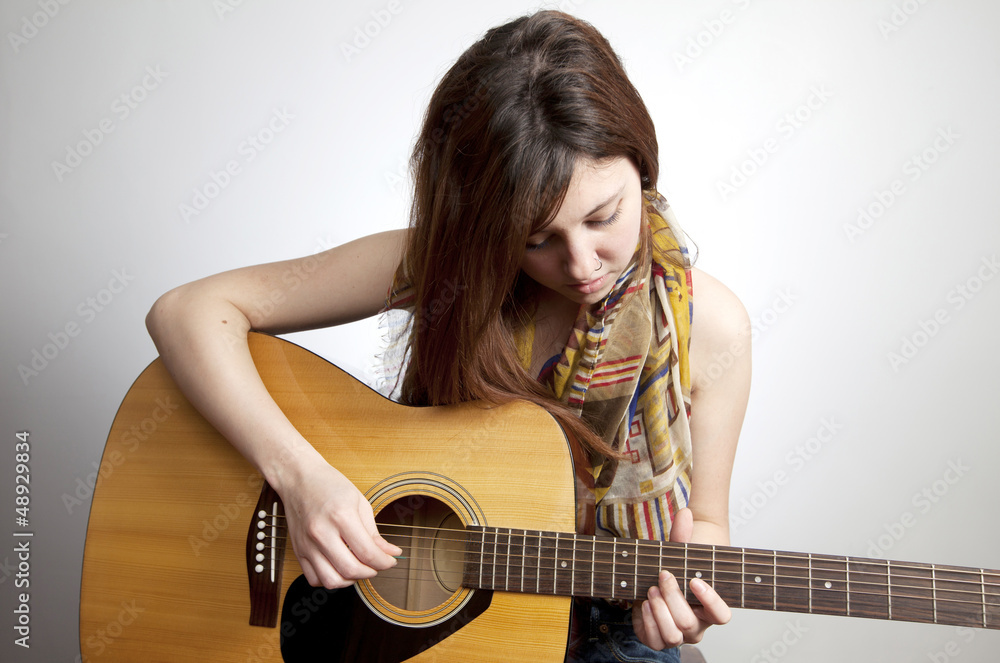 Young teenaged girl with nose ring playing acoustic guitar Young teenaged girl with nose ring playing acoustic guitar
