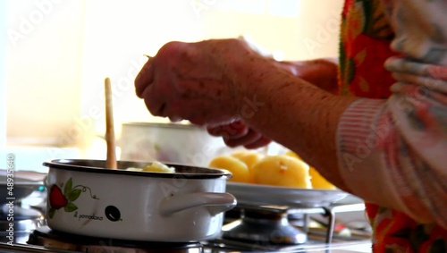 Elder woman in the kitchen, cooking lunch.