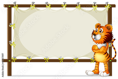 Fototapeta Naklejka Na Ścianę i Meble -  A tiger standing beside a wooden frame
