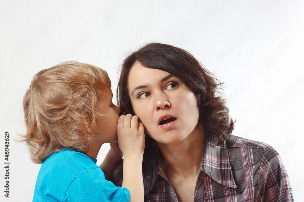 Little boy whispers to his mother something into her ear Little boy whispers to his mother something into her ear