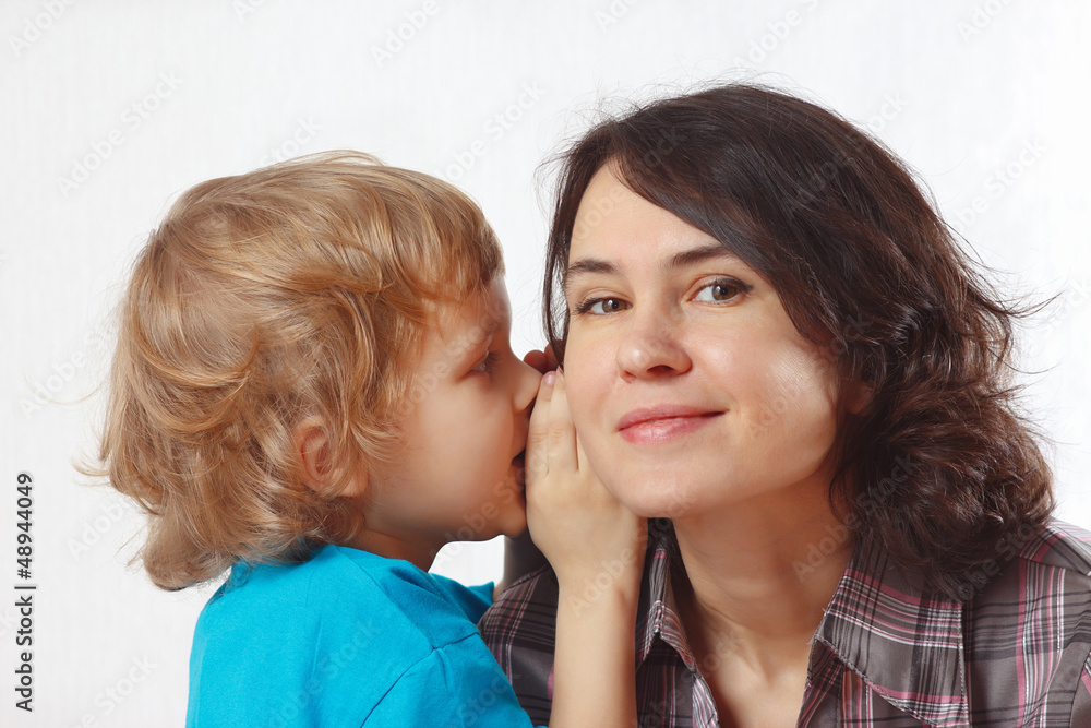 Young cute boy whispers secrets to his mother