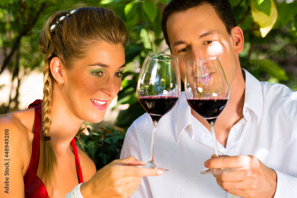 Woman and man in vineyard drinking wine