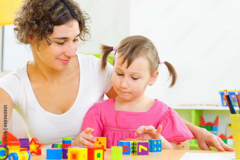 Young mother and little daughter playing with toy blocks Young mother and little daughter playing with toy blocks