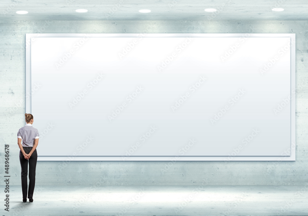 Business person standing near a blank billboard Business person standing near a blank billboard