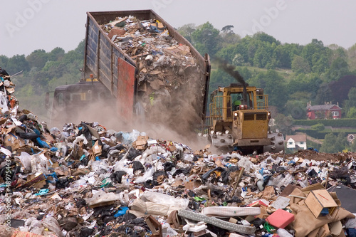 A bulldozer and garbage truck on a landfill waste site