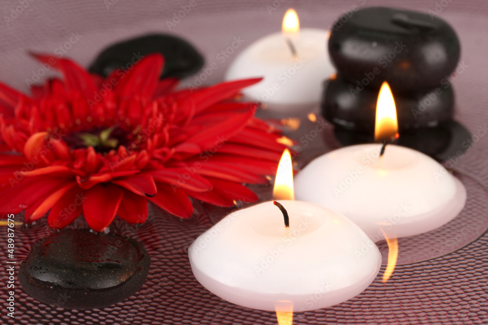 spa stones with flower and candles in water on plate spa stones with flower and candles in water on plate