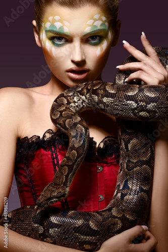 Serpent. Fantasy. Fancy Woman holding Tamed Snake in Hands