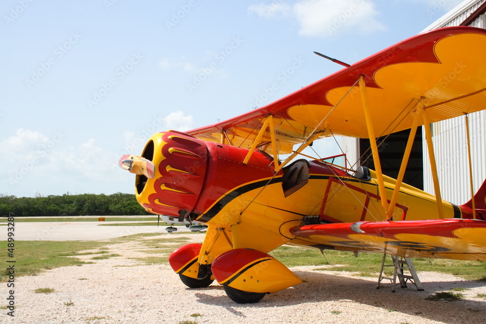 Fototapeta premium Colorful vintage airplane by a hanger