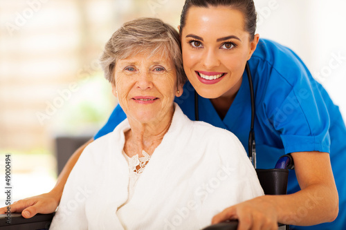 happy senior woman on wheelchair with caregiver