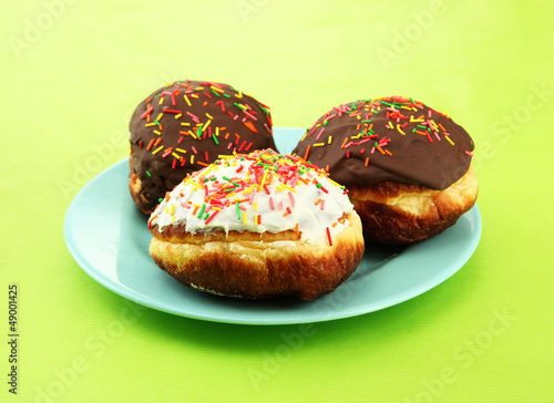 Tasty donuts on color plate on color background