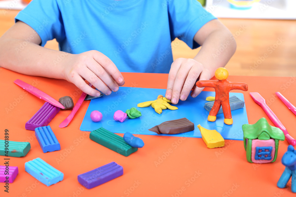 Child moulds from plasticine on table