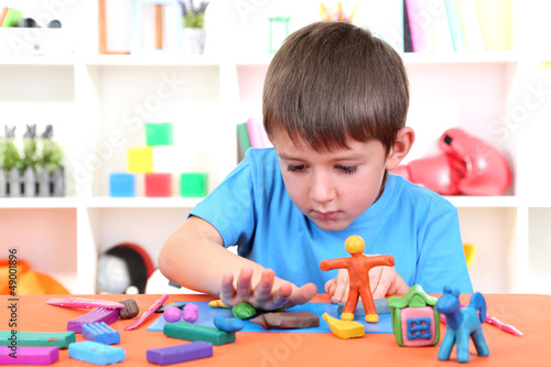 Cute little boy moulds from plasticine on table