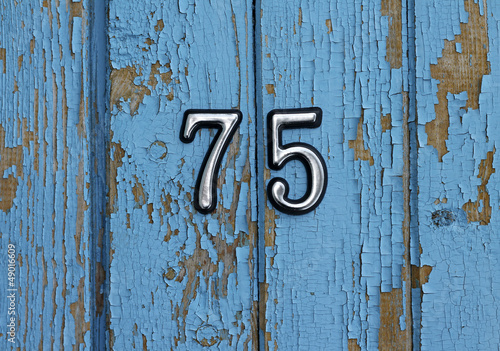number 75 on blue wooden wall, close-up
