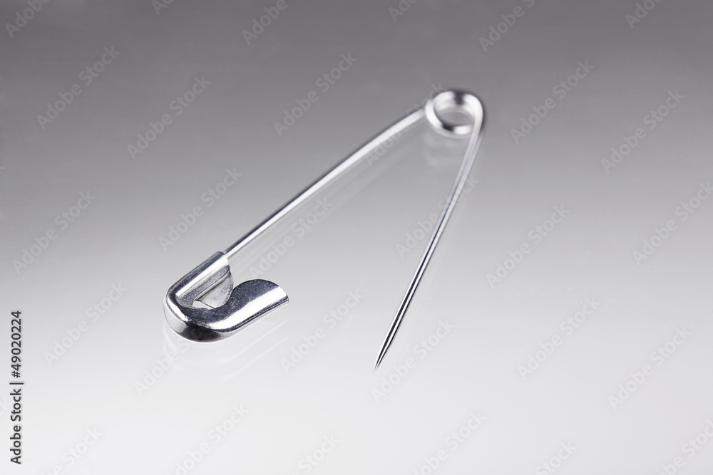 Isolated, open safety pin on grey background Isolated, open safety pin on grey background