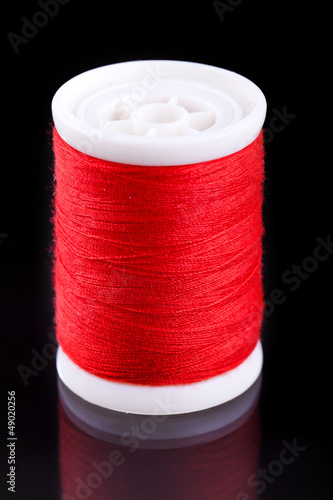 macro shot of red bobbin thread isoladed on black photo