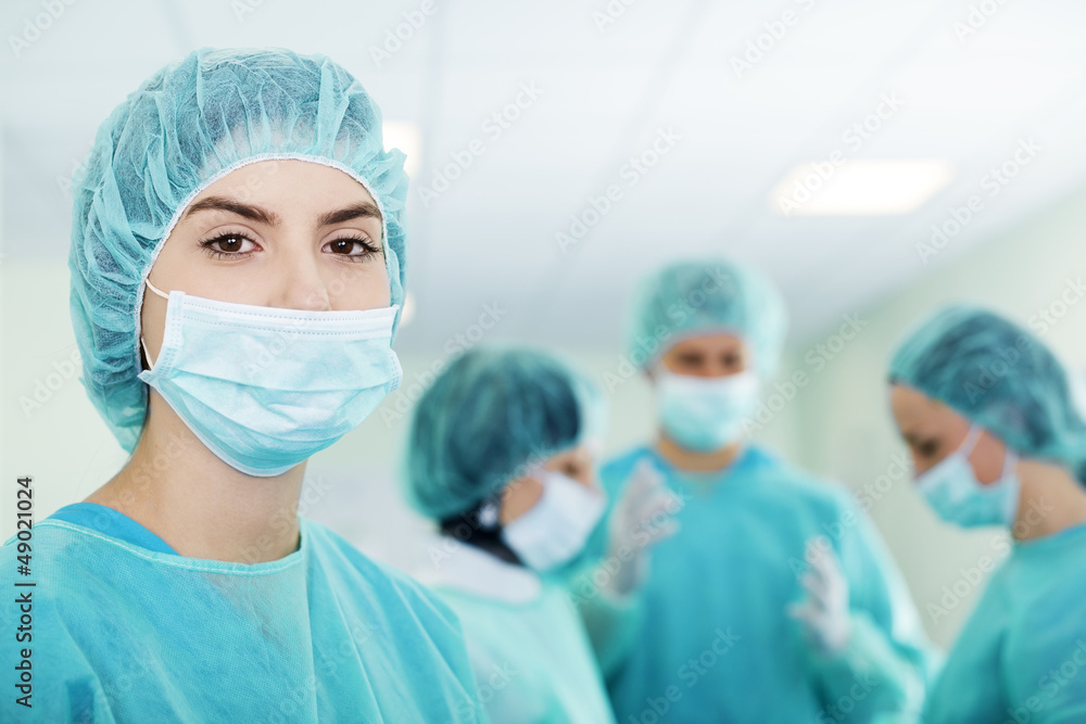 Young female surgeon with medical team in back before surgery Young female surgeon with medical team in back before surgery