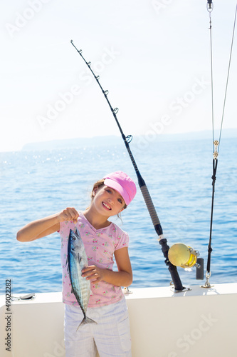 child little girl fishing in boat holding little tunny fish catc
