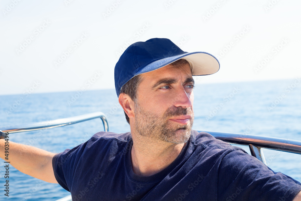 Sailor man at boat bow with cap looking away the sea