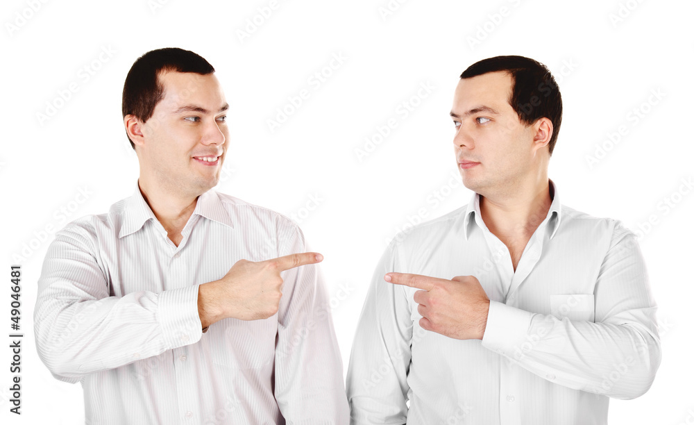 Two attractive smiling young men twins showing at each other Two attractive smiling young men twins showing at each other